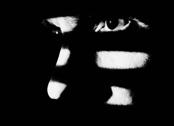 Man looking through window blind. High contrast, black &amp; white.