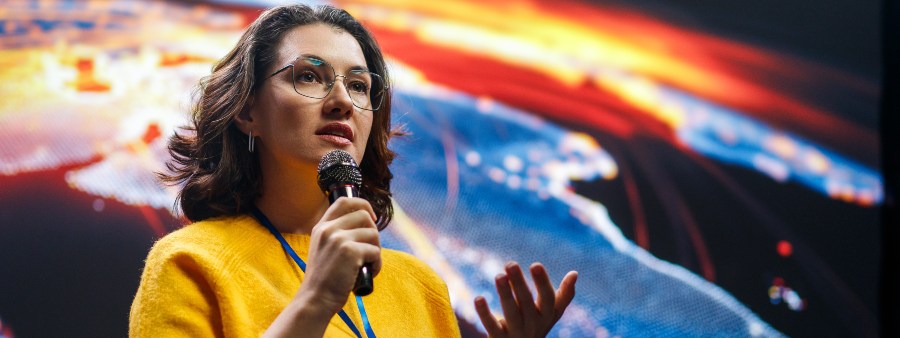 A young woman is giving a presentation at a conference.