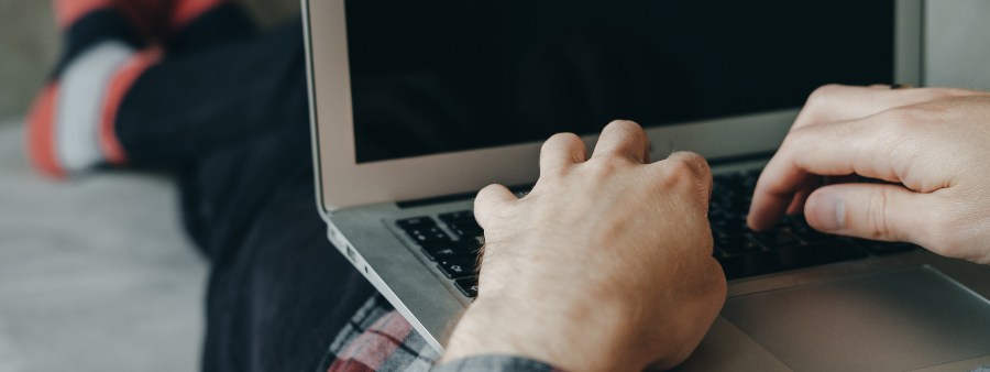 Hipster man in red socks working at laptop and lying  on the couch